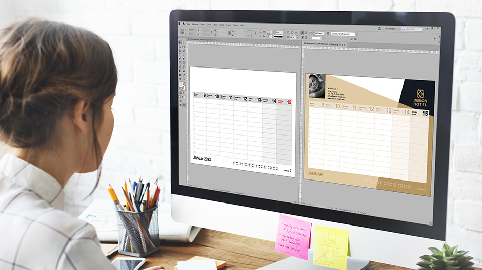 Eine Frau sitzt vor einem Bildschirm. Auf diesem sind zwei Kalenderseiten in Adobe InDesign geöffnet.