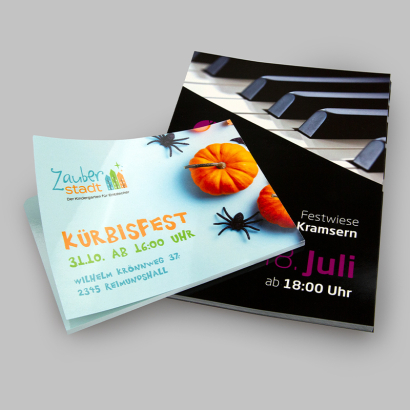 Flyer mit UV-Lack aufeinander liegend vor grauer Oberfläche