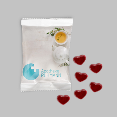 Individuell gestaltete Flowpacks gefüllt mit Fruchtgummi-Herzen vor grauem Hintergrund