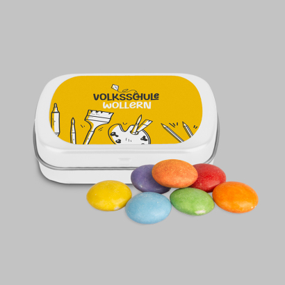 Personalisierte Mini-Klappdose mit bunten Schokolinsen daneben liegend auf grauem Hintergrund