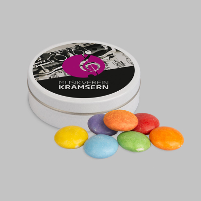 Individuell bedruckte XS-Taschendose daneben liegen bunte Schokolinsen auf grauem Hintergrund