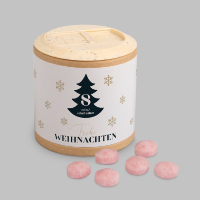 Individuell bedruckte Papier-Werbedose, Glühweinbonbons daneben liegend auf grauem Hintergrund