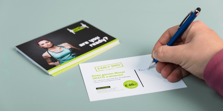 Jemand schreibt auf eine bedruckte Postkarte