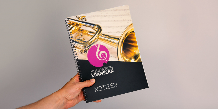 Jemand hält einen bedruckten Collegeblock