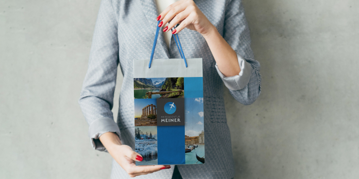 Frau hält eine Papiertragetasche mit PP-Kordel in die Höhe, die individuell bedruckt wurde