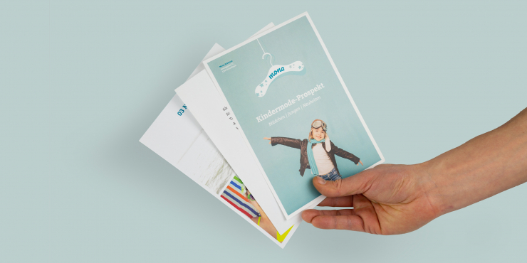 Jemand hält bedruckte Loseblattsammlungen vor Türkisen Hintergrund