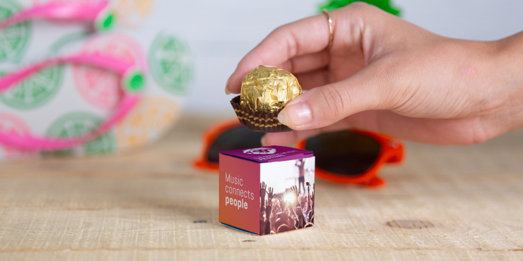 Hand hält eine Praline über eine individuell gestalteten Schachtel