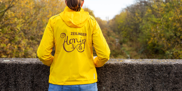 Eine Frau trägt eine gelbe Flint Elevate Jacke mit Druck