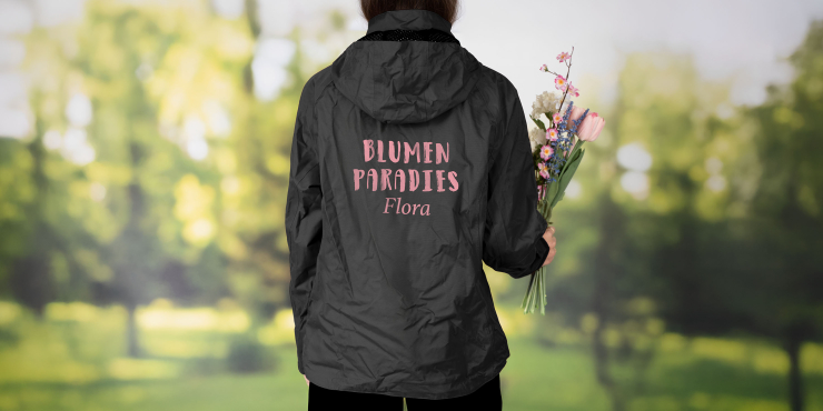 Eine Frau trägt eine bedruckte Hydraplus Russell Jacke und hält Blumen in der Hand