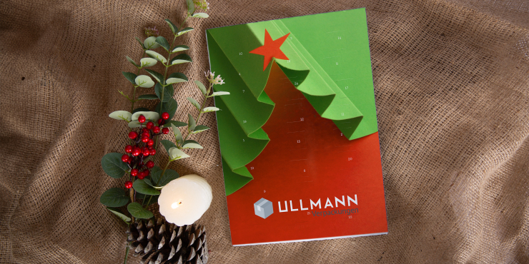 Bedruckter Reinpapier-Adventkalender auf bräunlichem Hintergrund mit weihnachtlicher Dekoration