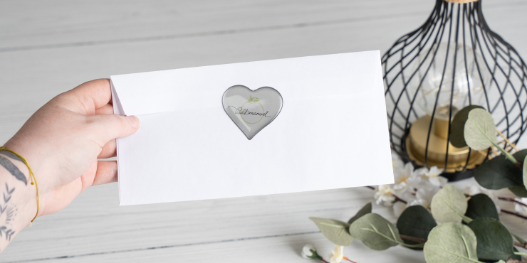 Person hält ein Kuvert mit einem Doming Sticker in Herzform