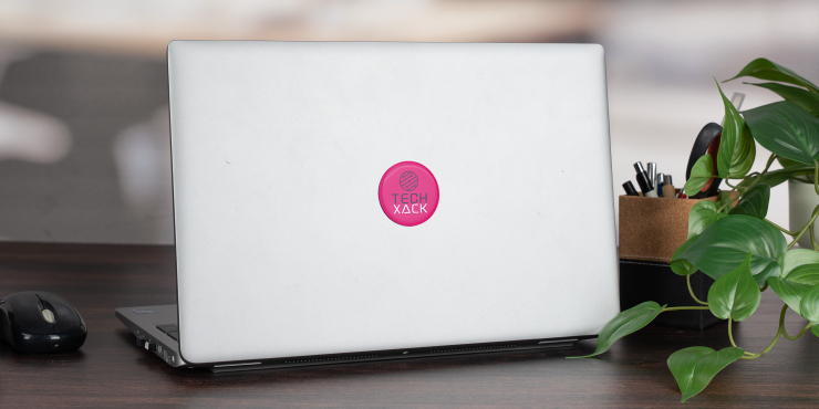 Laptop mit einem runden Doming Aufkleber steht auf einem Schreibtisch