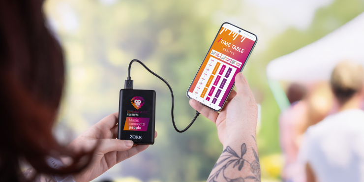 Person hält Smartphone in der Hand, das gerade mit einer individuell gestalteten Powerbank aufgeladen wird