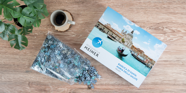 Puzzleteile befinden sich in einem Sack neben der Schachtel