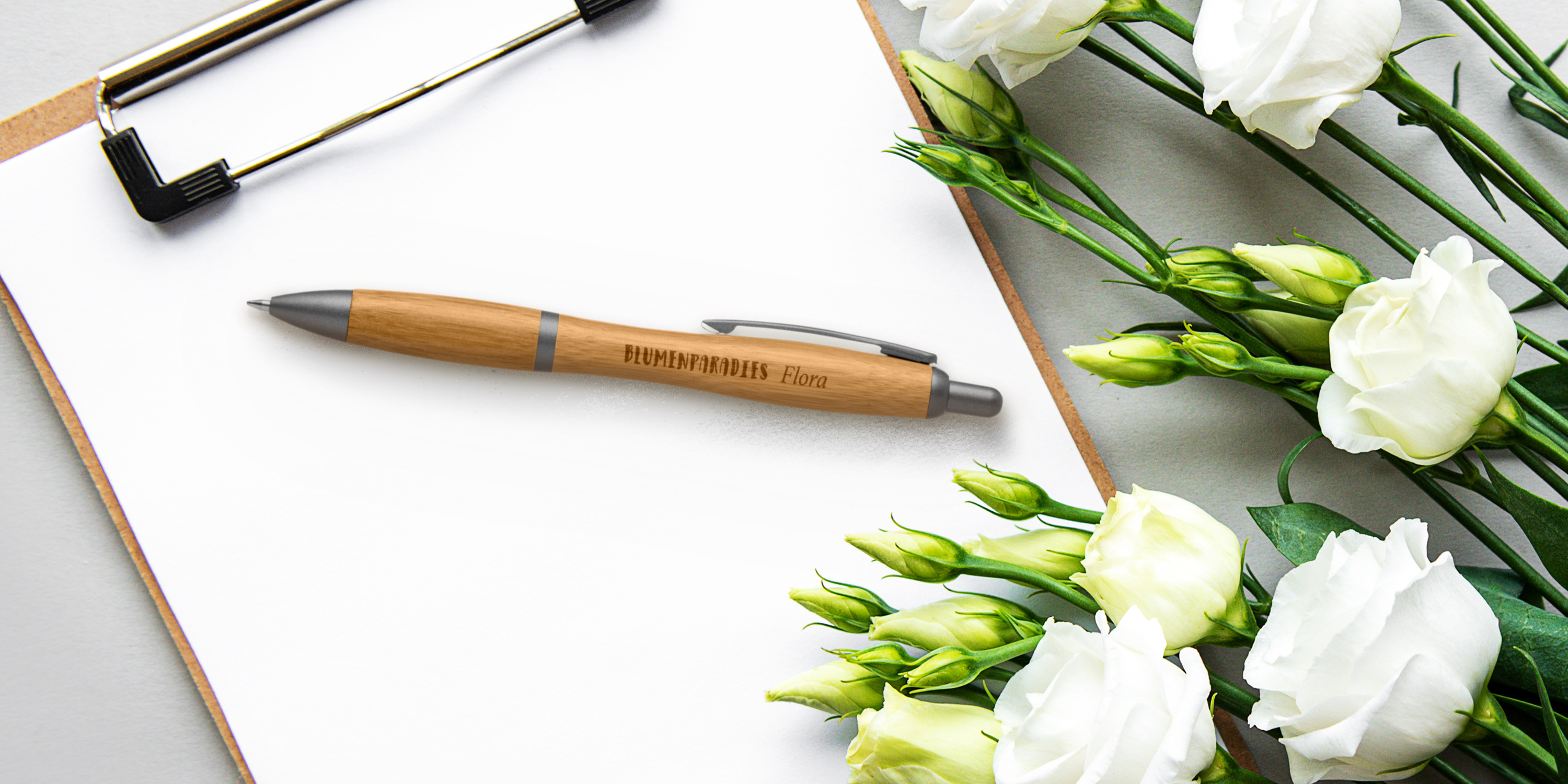 Stift liegt auf Klemmbrett mit Blumen