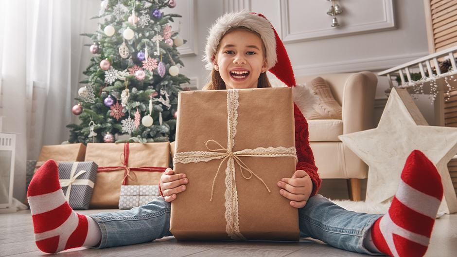 Kind mit Weihnachtsmütze und Weihnachtsgeschenken