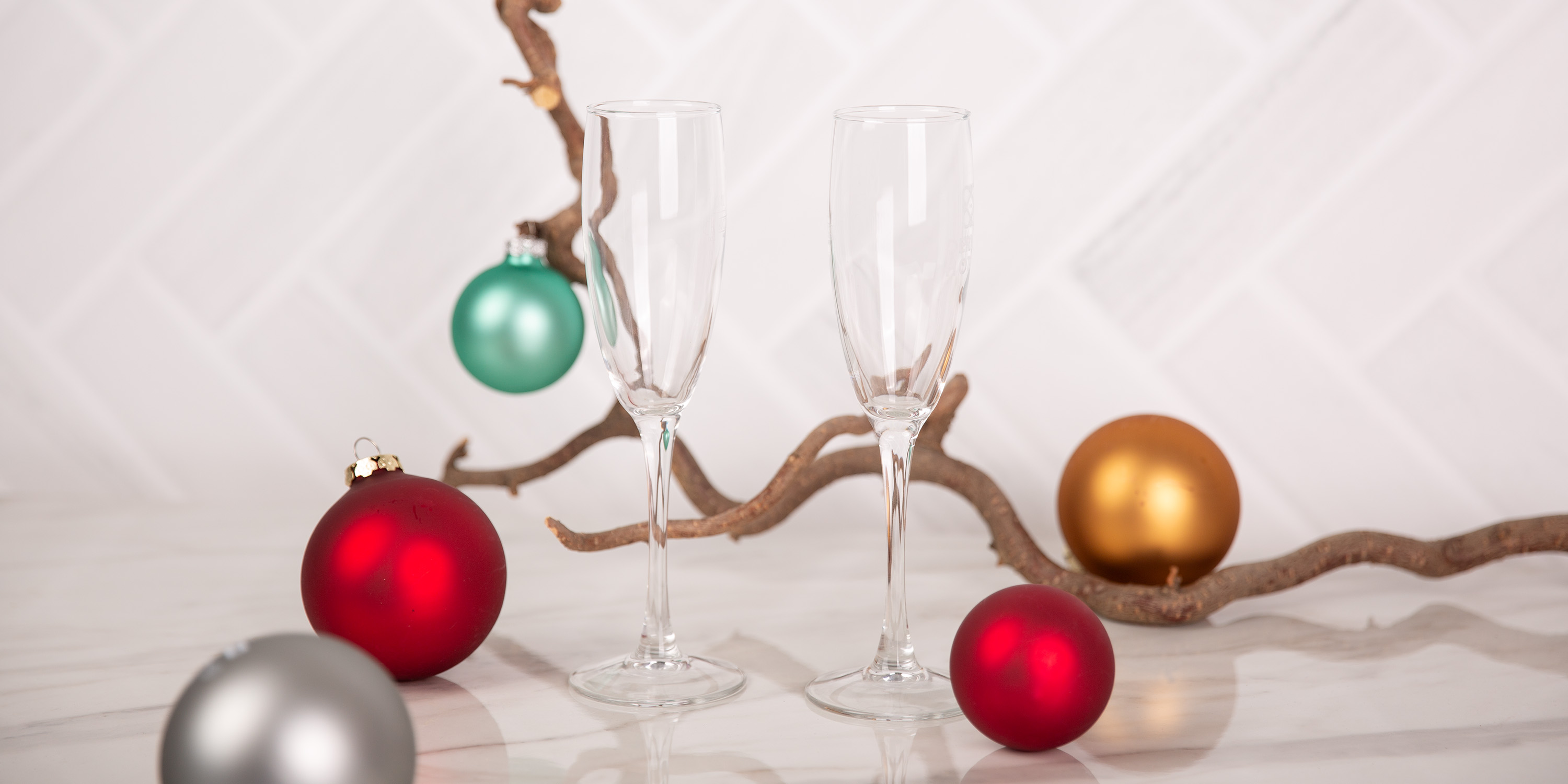 Zwei Sektgläser mit Weihnachtskugeln auf einem grauen Hintergrund