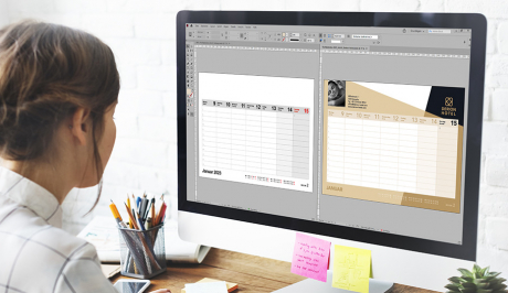 Eine Frau sitzt vor einem Bildschirm. Auf diesem sind zwei Kalenderseiten in Adobe InDesign geöffnet.