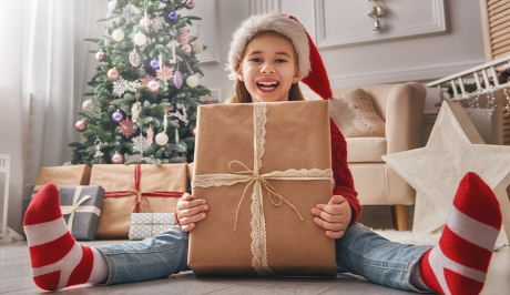 Kind mit Weihnachtsmütze und Weihnachtsgeschenken