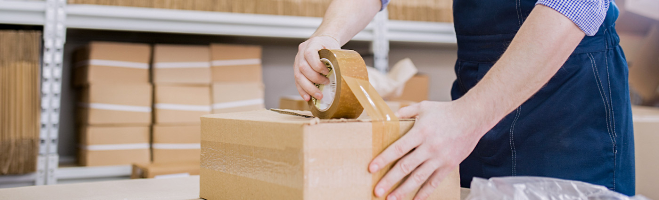 Ausschnitt auf dem ein Mann gerade ein Paket verpackt