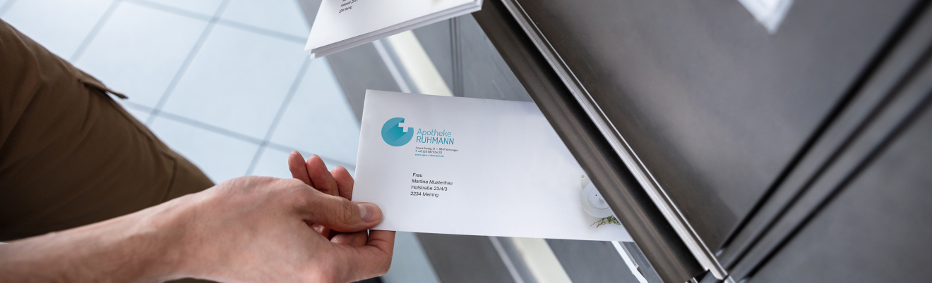 Person steckt personalisierten Brief durch Postkastenschlitz