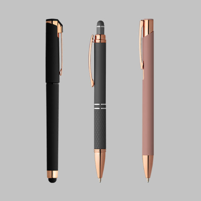 Schreibgeräte mit Goldakzenten auf grauem Hintergrund