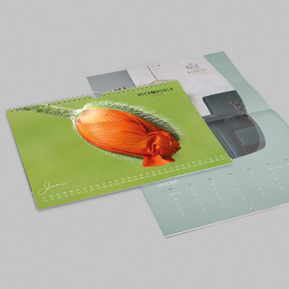 individuell bedruckter Wandkalender / Broschürenkalender vor grauer Oberfläche