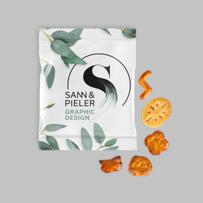 Eine Tüte mit verschiedenen Knabberartikeln wie Brezeln, Crackern und anderen Snacks auf grauem Hintergrund