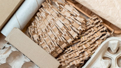 Versandkarton gefüllt mit Papierstreifen, leerer Klopapierrolle und Karton.