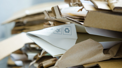 Ein Papierhaufen bei dem ein Stück Recyclingpapier hervorsteht. 