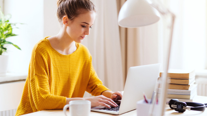 EIne Frau sitzt an ihrem Schreibtisch vor einem Laptop.
