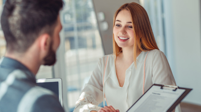 Ein Mann und eine junge Frau sitzen sich gegenüber im Bewerbungsgespräch.