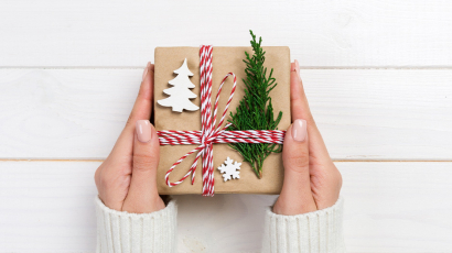 Frau hält ein Paket in der Hand das weihnachtlich geschmückt ist