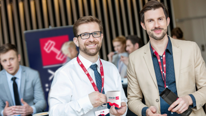 Zwei Mitarbeiter stehen bei einer Konferenz und tragen bedruckte Lanyards