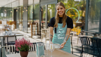 Eine Gastro-Mitarbeiterin serviert gerade einen Kaffee