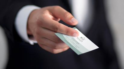 Eine Hand streckt eine Visitenkarte aus