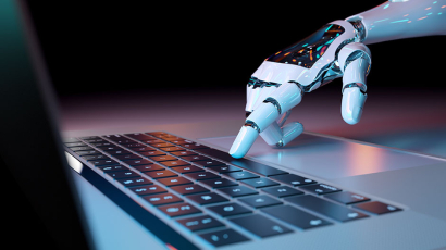 Eine Roboter-Hand berührt die Tasten eines Laptops.