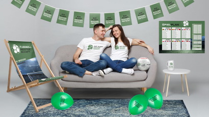 Zwei Personen sitzen auf einem Sofa, um sie herum sind verschiedene Produkte zu sehen.