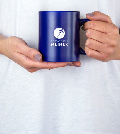 Person die eine individuell bedruckte Tasse in der Hand hält.