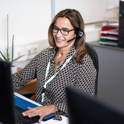 Mitarbeiterin sitzt mit Headset am Computer
