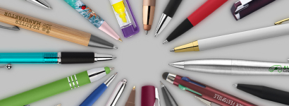 diverse Schreibgeräte im Kreis aufgelegt auf grauem Hintergrund