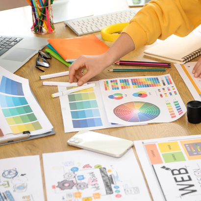 Auf einem Tisch liegen diverse Grafiken und Farben