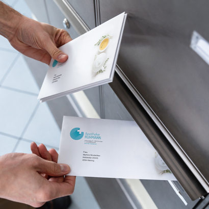 Eine Person wirft Briefe in einen Postkasten