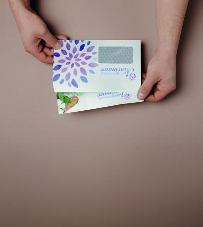 Person hält zwei bedruckte Kuverts in der Hand auf braunem Hintergrund