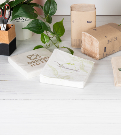 Bedruckte Servietten liegen auf einem weißen Tisch neben einer Pflanze