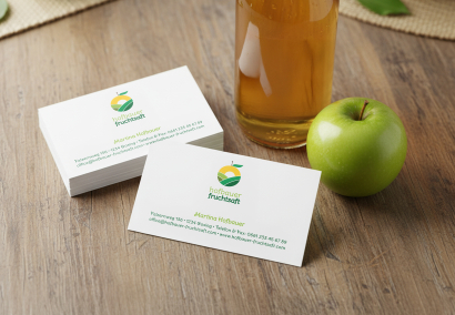 Klassische Visitenkarten bedruckt in Kleinmenge stehen neben einem Apfel und einer Flasche Apfelsaft