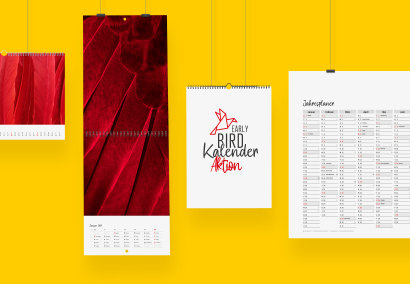 Verschiedene bedruckte Kalender hängen auf einer gelben Wand und zeigen die Early Bird Aktion