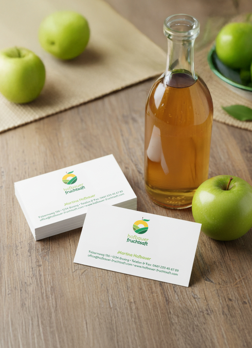 Klassische Visitenkarten bedruckt in Kleinmenge liegen neben Äpfel und einer Flasche Apfelsaft auf einem Tisch
