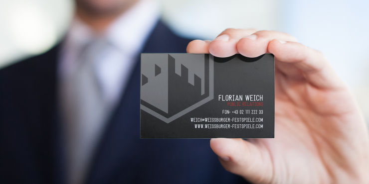 Mann hält Bestpreis-Visitenkarte mit extra-dickem Material hoch
