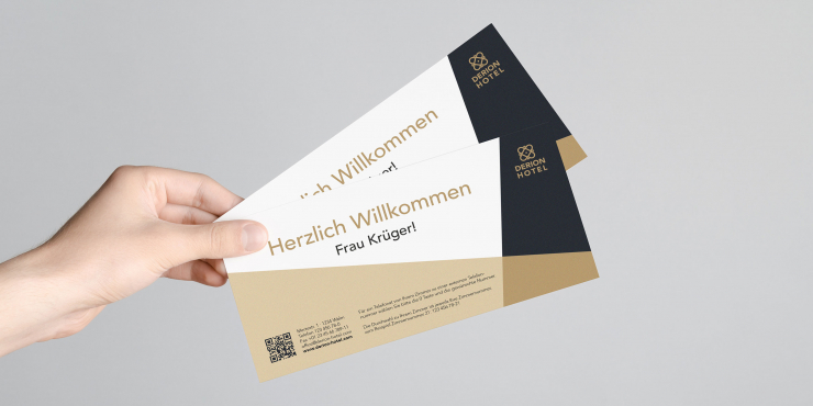 Jemand hält Briefpapier mit Goldfarbe vor grauem Hintergrund